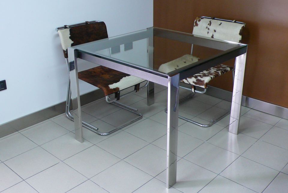 tavolo quadrato in stile moderno con ripiano in vetro, struttura in metallo verniciato e piedi in acciaio inox lucido