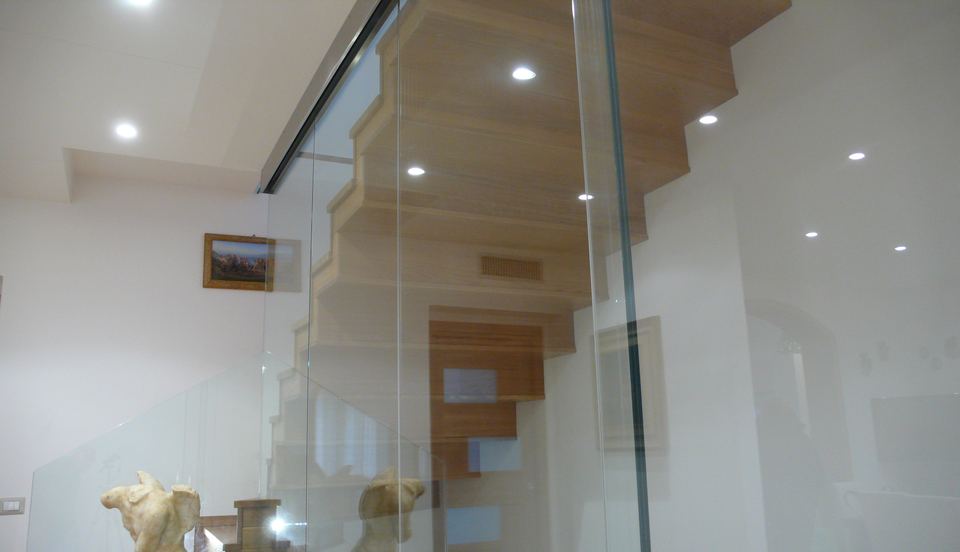 Dettaglio moderno parete e porta scorrevole in vetro con binario a vista in acciaio inox satinato